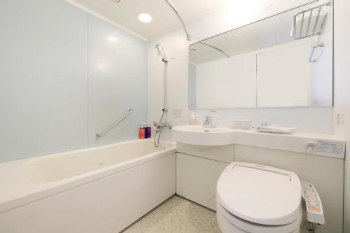 a white bathroom with a toilet and a sink at Richmond Hotel Premier Sendai Ekimae in Sendai