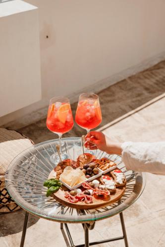 two people holding wine glasses with a plate of food on a table at BAYIT Charming Place in Polignano a Mare