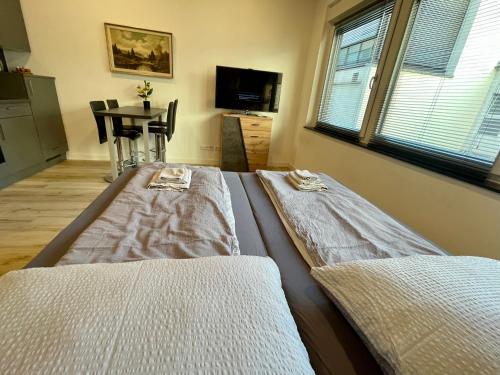 two beds in a room with a table and window at NEU Schwarzwald Zimmer am Schlössle Goldstadt Pforzheim in Pforzheim