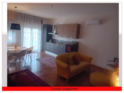 a living room with a chair and a table and a kitchen at Casa del Sole in Mondragone