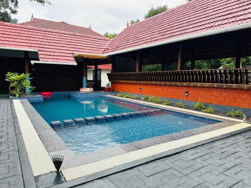 a swimming pool in front of a house at Riverbliss - River Retreat with Private Pool in Talavadi