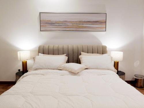 a bedroom with a large white bed with two lamps at Luxurious Apartment in The Pearl, Qatar in Doha