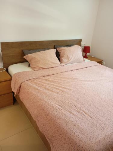 een bed met een roze deken en kussens erop bij Condado de Alhama Golf resort - Villa Alba in Alhama de Murcia