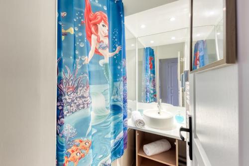 La salle de bains est pourvue d'un rideau de douche de bonne et d'un lavabo. dans l'établissement Cosy Home / Disney / Val d'Europe / Paris, à Serris