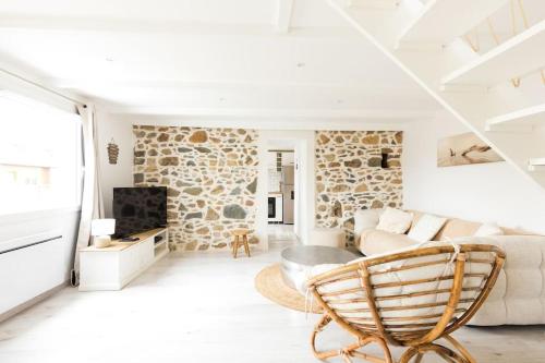 - un salon blanc avec un mur en pierre dans l'établissement Charmante maison familiale à 10 minutes des plages, à Plougrescant