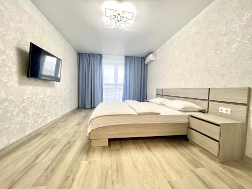 a bedroom with a bed and a television on a wall at ApartPoltava Нові апартаменти ремонт цього року ПАНОРАМА, Корпусний парк, Найкраща локація in Poltava