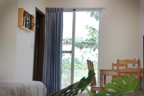 a bedroom with a large window and a plant at Hakka Eco-farm 雅歌園民宿食農教育有機農場 in Wanluan