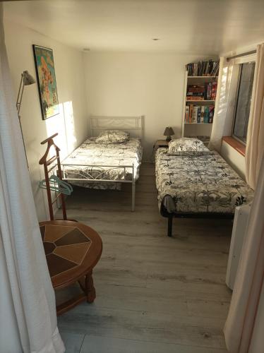 a room with two beds and a chair and a table at KITOKO L'HERAULT gite close to SALAGOU Lake in Clermont-lʼHérault