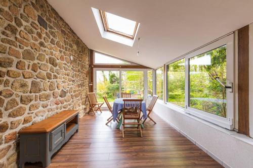 une salle à manger avec une table et un mur en pierre dans l'établissement Belle maison chaleureuse à 50m de la mer, à Lanmodez