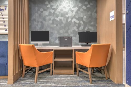 a desk with two monitors and two chairs at HOLIDAY INN EXPRESS & SUITES DALLAS PLANO NORTH by IHG in Plano
