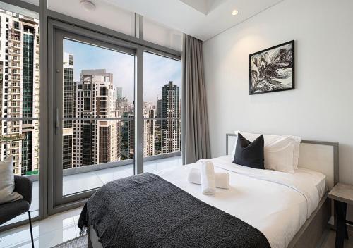 a bedroom with a bed and a large window at Bright High Floor Apartment in a 5 Star Hotel Resident Tower w Burj View and access to 64th Infinity Pool, Gym, Sauna, Spa, Restaurants, Bars and more in Dubai