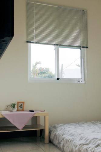 a bedroom with a window with a bed and a table at Hakka Eco-farm 雅歌園民宿食農教育有機農場 in Wanluan