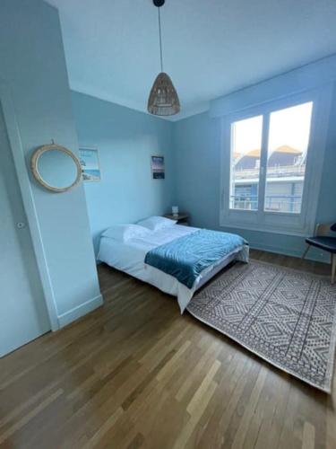 Cette chambre bleue comprend un lit et une fenêtre. dans l'établissement Appartement rénové hyper-centre, à Saint-Nazaire