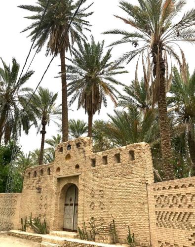 a brick building with palm trees in the background at Dar Tozria in Tozeur
