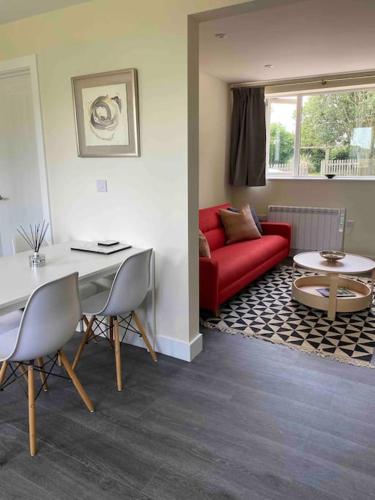 a living room with a red couch and a table at Larks Leaze Lodge, Steeple Ashton, Wiltshire in Trowbridge