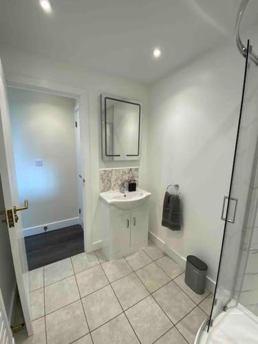 a white bathroom with a sink and a mirror at Larks Leaze Lodge, Steeple Ashton, Wiltshire in Trowbridge