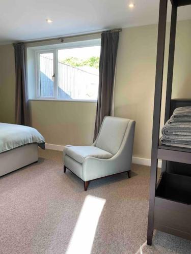 a bedroom with a chair and a bed and a window at Larks Leaze Lodge, Steeple Ashton, Wiltshire in Trowbridge