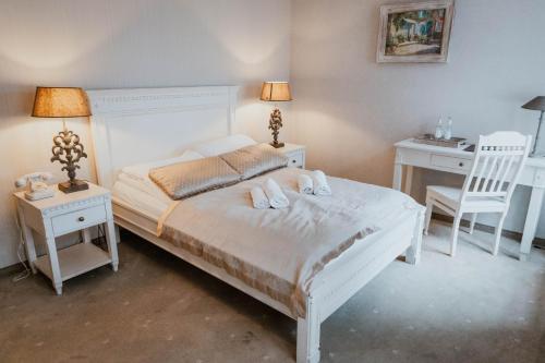 a bedroom with a white bed with two tables and a chair at Hotel Adler in Byczyna
