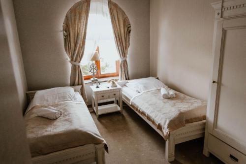two beds in a small room with a window at Hotel Adler in Byczyna