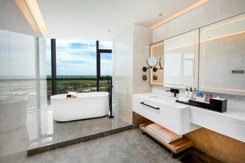 a bathroom with a tub and a sink and window at Latsavong Wanda Vista Vientiane in Vientiane