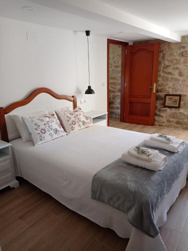 a bedroom with a large white bed with two pillows at El Legado de Acha in Cambados