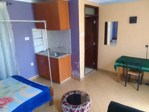 a room with a bed and a sink and a table at Self Contained Studio around Alango School, Wathorego, Kajulu in Kisumu