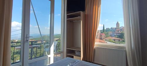 a room with a balcony with a view of a city at Guest House Alazani Valley in Sighnaghi