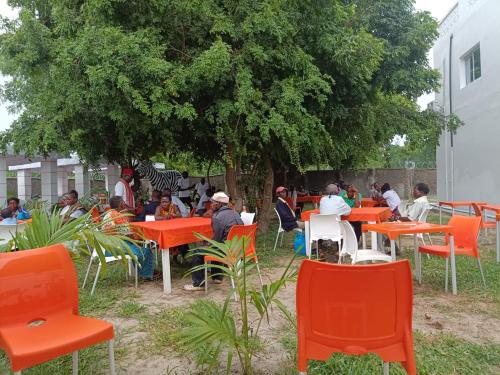 a group of people sitting at tables under a tree at Butah Gardens Watamu in Gede
