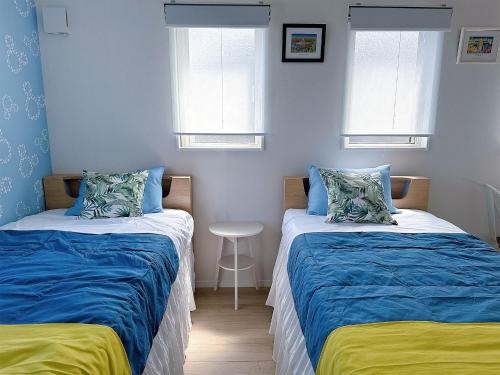 two beds in a room with blue walls and windows at Goldcoast IKI B&B in Iki