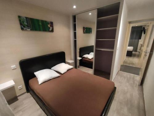 une petite chambre avec un lit et un miroir dans l'établissement Le T3 de Julien, à Tarbes