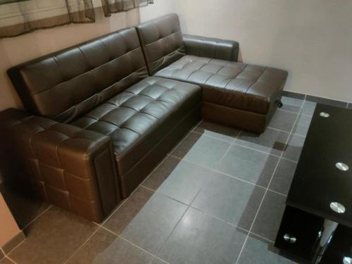 un canapé en cuir brun assis dans une pièce dans l'établissement Le T3 de Julien, à Tarbes