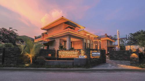 a house with a palm tree in front of it at Xishuangbanna Sadu Lanmei Resort Hotel in Jinghong