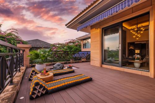 a deck with pillows on a house at Xishuangbanna Sadu Lanmei Resort Hotel in Jinghong