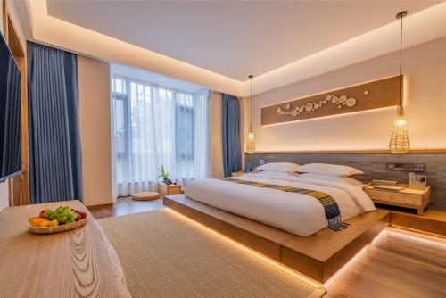 a large bedroom with a large bed and a table at Xishuangbanna Sadu Lanmei Resort Hotel in Jinghong