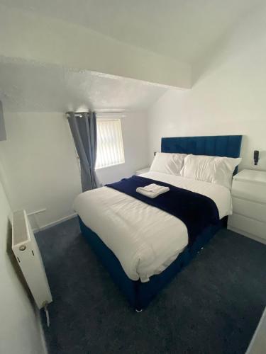 a bedroom with a large bed with a blue headboard at The New ATLAS HOTEL in Blackpool