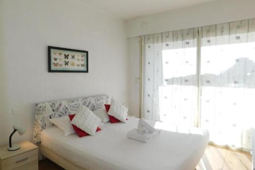 une chambre avec un lit blanc avec des oreillers et une fenêtre dans l'établissement La Marina - T2 Apartment, à Villeneuve-Loubet