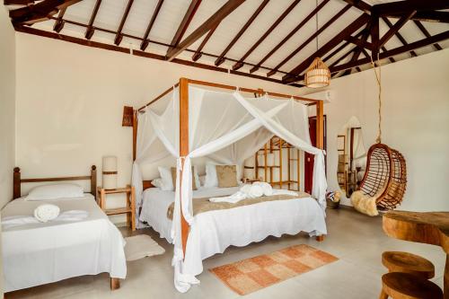 a bedroom with two beds and a canopy bed at Pousada Villa Tainá - Arraial d'Ajuda, Bahia in Arraial d'Ajuda