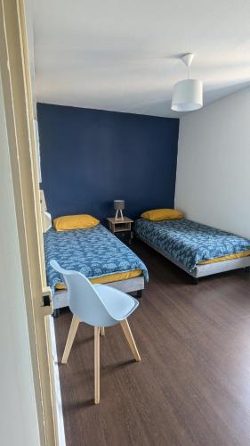 une chambre avec deux lits et une chaise dedans dans l'établissement le gîte de la ruelle, à Neuvy-sur-Loire
