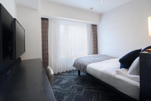 a hotel room with a bed and a flat screen tv at HOTEL MYSTAYS Hamamatsucho in Tokyo