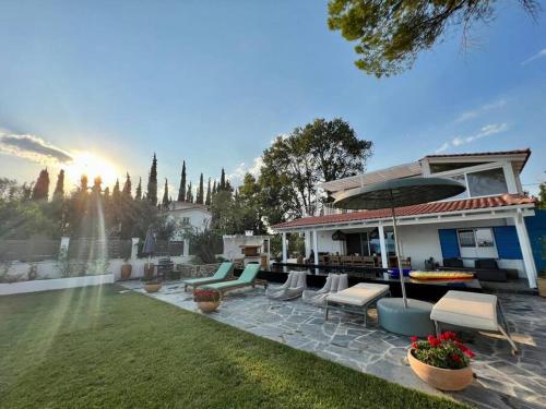 a house with a patio with chairs and a garden at Evia Escape - Beachfront villa in Skála