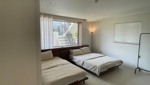 due letti in una stanza con finestra di Seha Stay a Suncheon