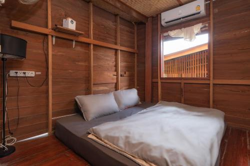 uma cama num quarto com paredes de madeira e uma janela em Serene Escape in Pai em Ban Wiang Nua