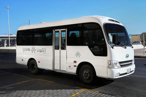 a white bus parked in a parking lot at La Cordia Hotel Apartment in Al Madinah