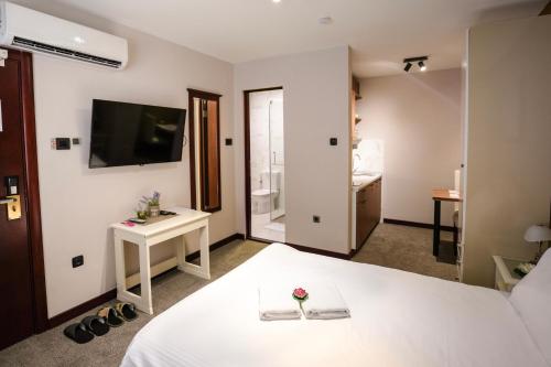 a bedroom with a white bed and a television at Apartmani Element in Novi Sad