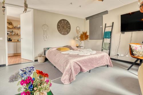 a bedroom with a bed with a pink blanket and flowers at Appartement YCW 'Papillon' in Rijnsaterwoude
