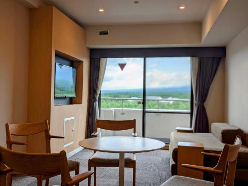 a living room with a table and chairs and a large window at Hotel Regina Kawaguchiko in Fujikawaguchiko