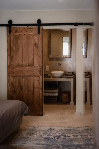 La salle de bains est pourvue d'une porte en bois et d'un lavabo. dans l'établissement Le mas de Roussillon chambre d'hôtes, à Roussillon