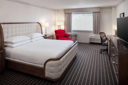 a hotel room with a large bed and a red chair at Hilton Chicago/Northbrook in Northbrook
