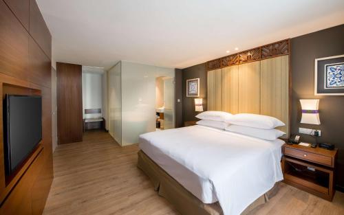 a bedroom with a large white bed and a flat screen tv at DoubleTree Resort by Hilton Hotel Penang in Batu Ferringhi
