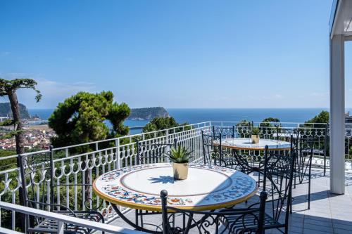 two tables and chairs on a balcony with the ocean at RIAMA AGRIRESORT in Naples